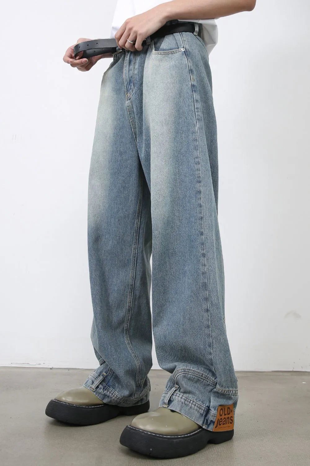 Baggy medium wash denim jeans with distressed detailing and a leather patch.