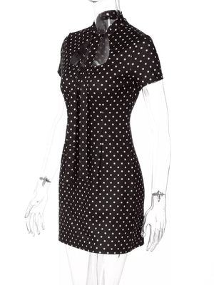 Chic black polka dot mini dress with short sleeves and a cut-out neckline with bow detail.