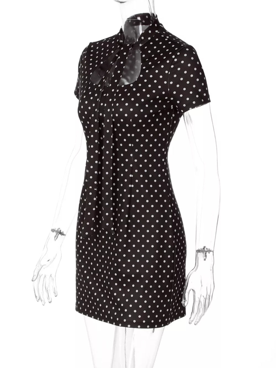 Chic black polka dot mini dress with short sleeves and a cut-out neckline with bow detail.