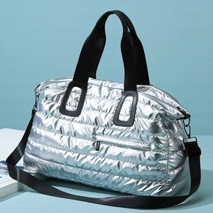Silver glossy padded weekend holdall with black straps and a zippered front pocket.