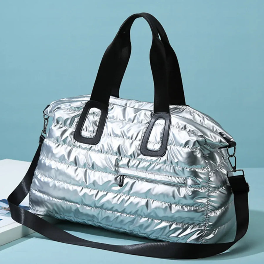 Silver glossy padded weekend holdall with black straps and a zippered front pocket.