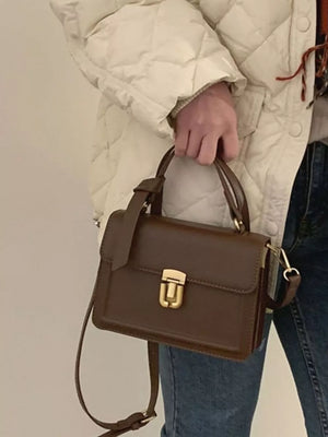 Small coffee pu leather crossbody bag with gold turn-lock closure and top handle.