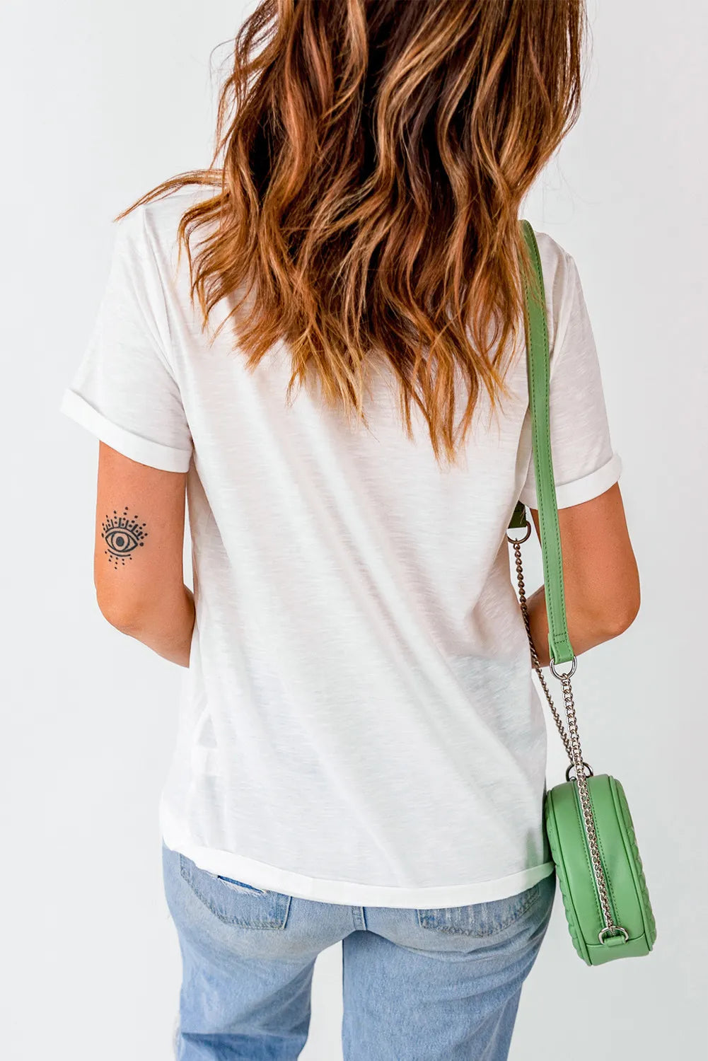 White cotton t-shirt with rolled sleeves and an eye tattoo on the arm.