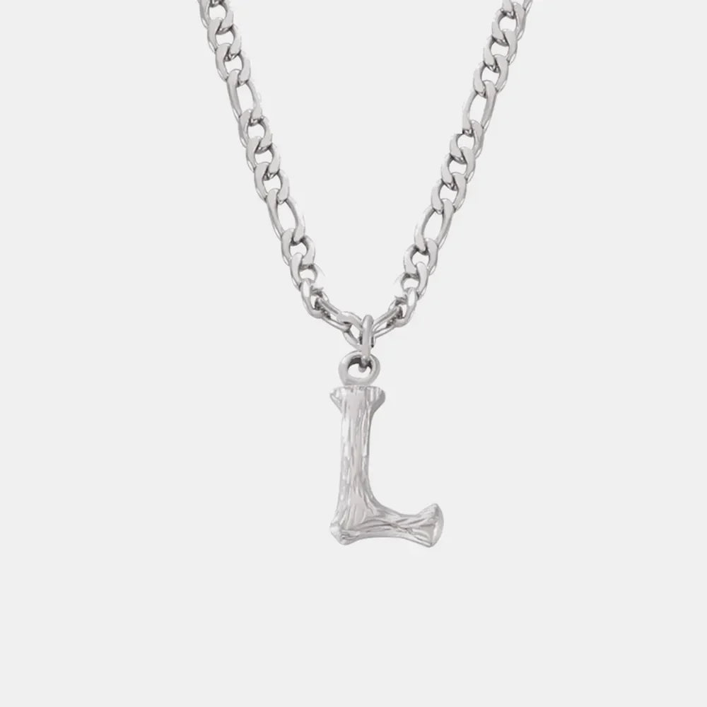 Textured initial pendant necklace with a silver chain and 'L' charm.