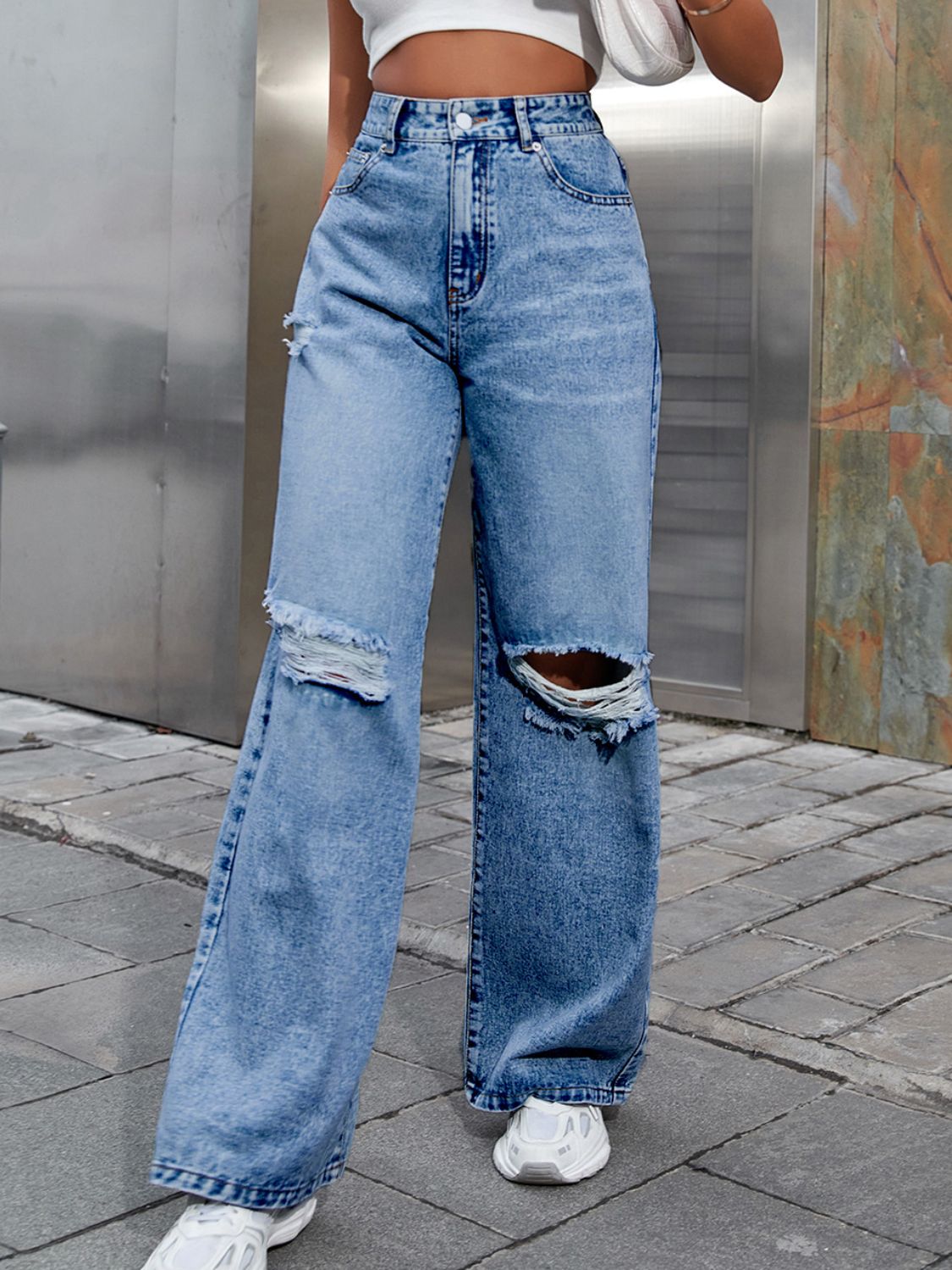 Distressed flare jeans in light wash denim with ripped knees.