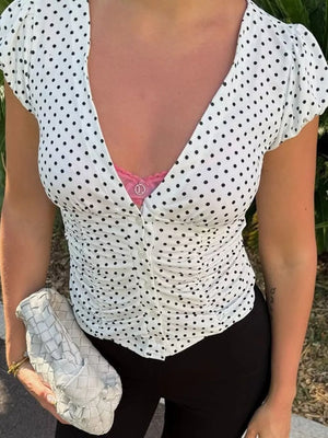 White polka dot ruched t-shirt with V-neck and short sleeves.