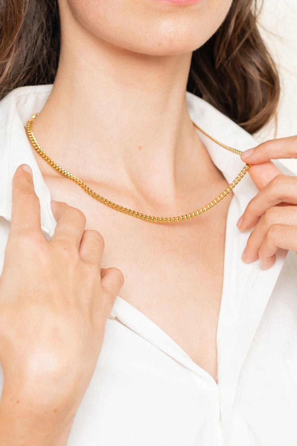 Sculpted gold chain necklace with 18K gold plating, worn as a choker.