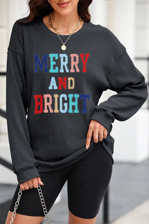 Textured ribbed sweatshirt in black with colorful "Merry and Bright" graphic.