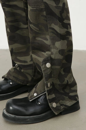 Camouflage utility flare trousers with snap-button leg details and zippers, styled with black boots.