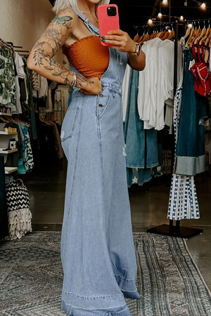 Distressed light wash denim overalls with wide legs and button closure.