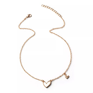 Gold alloy necklace with two heart charms, one large white heart and a small gold heart.