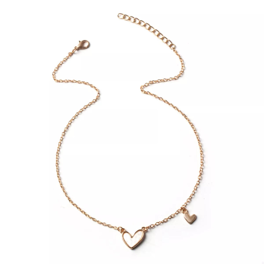 Gold alloy necklace with two heart charms, one large white heart and a small gold heart.