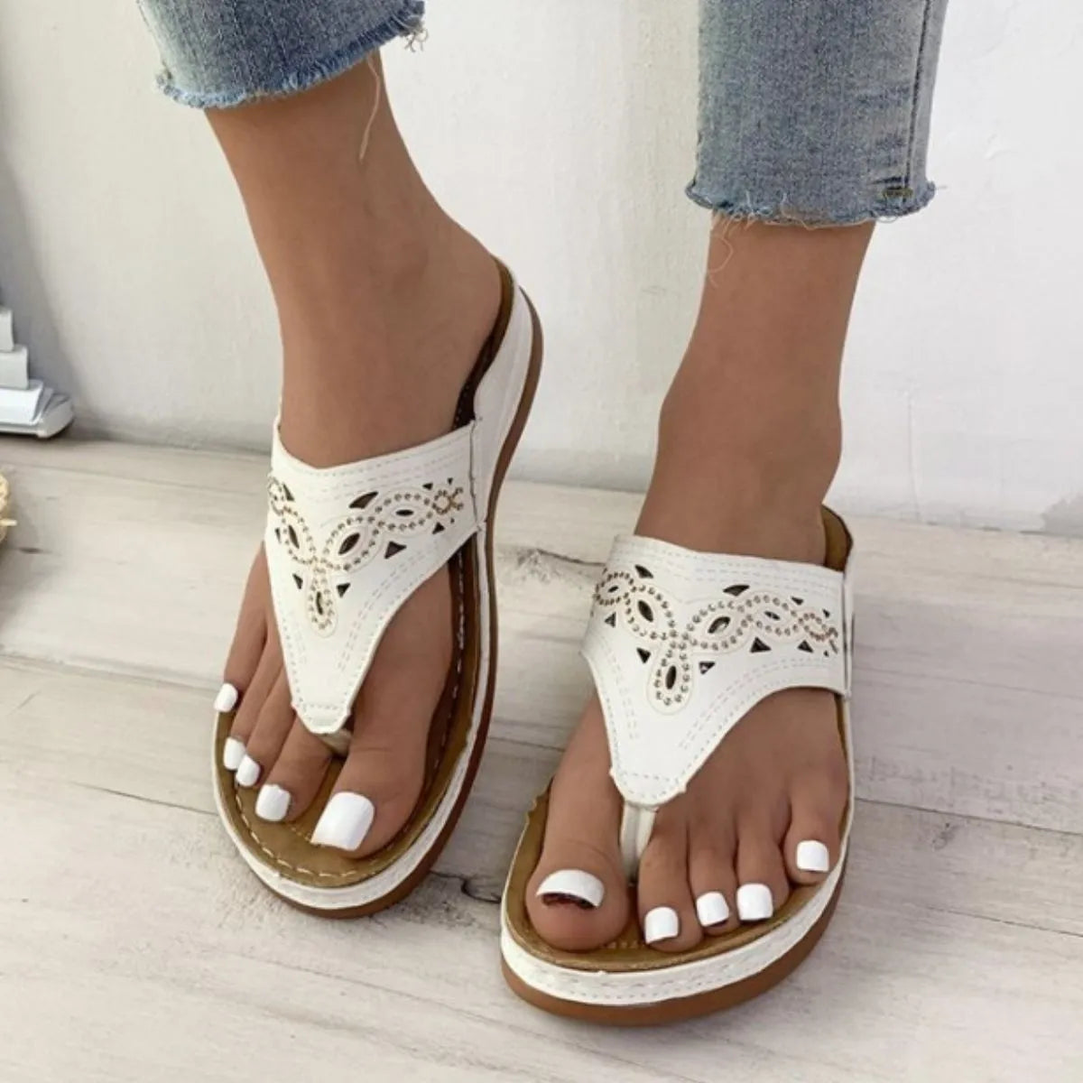 White laser-cut thong sandals with architectural detail and comfortable sole.