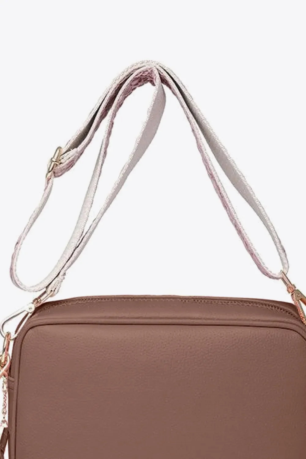 Textured crossbody bag in brown with a patterned strap and tassel detail.