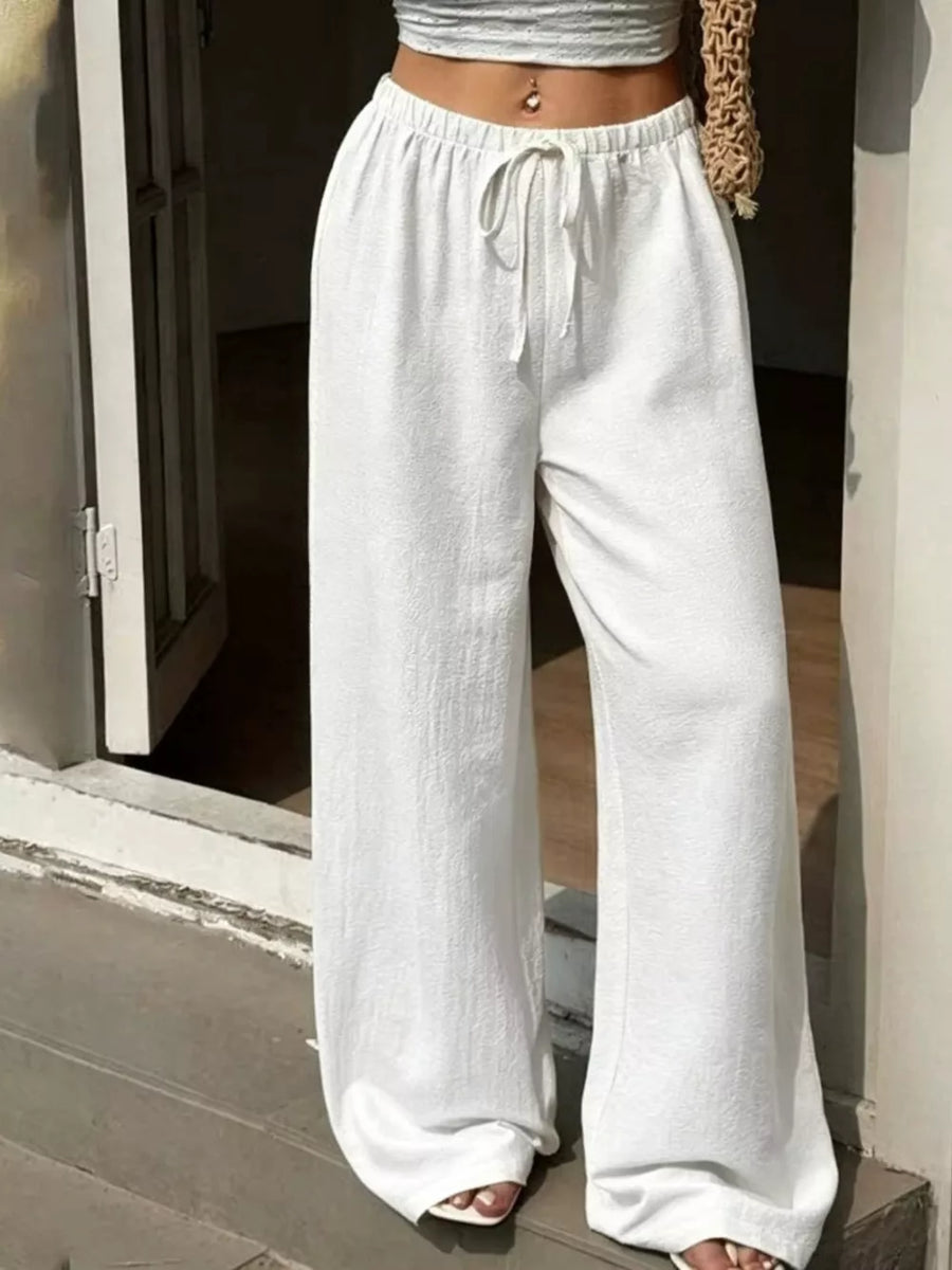White linen blend wide leg pants with drawstring waist and textured fabric.