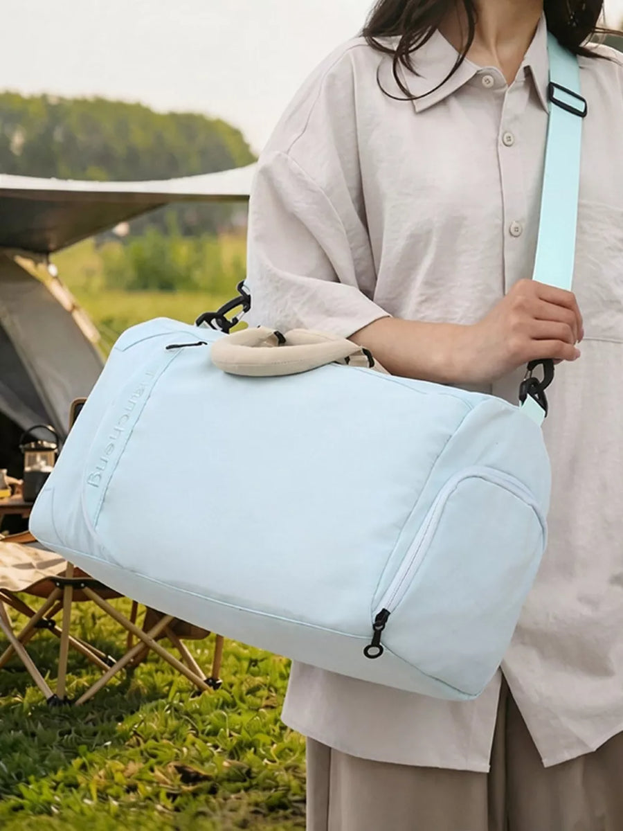 Light blue duffel bag with padded handles and a zippered side pocket, worn with a light beige shirt.