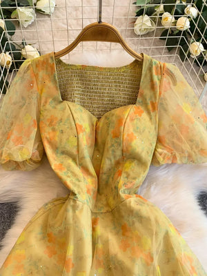 Yellow floral print maxi dress with sweetheart neckline, smocked bodice, and sheer puff sleeves.