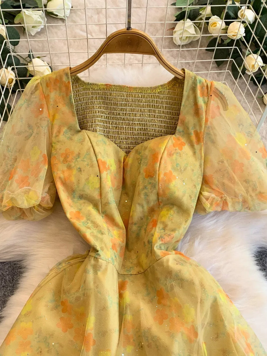 Yellow floral print maxi dress with sweetheart neckline, smocked bodice, and sheer puff sleeves.