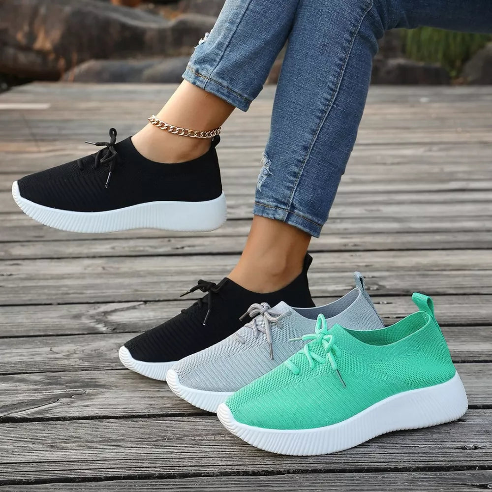 Black, light green, and gray lace-up sneakers with white mid soles and breathable knit uppers.