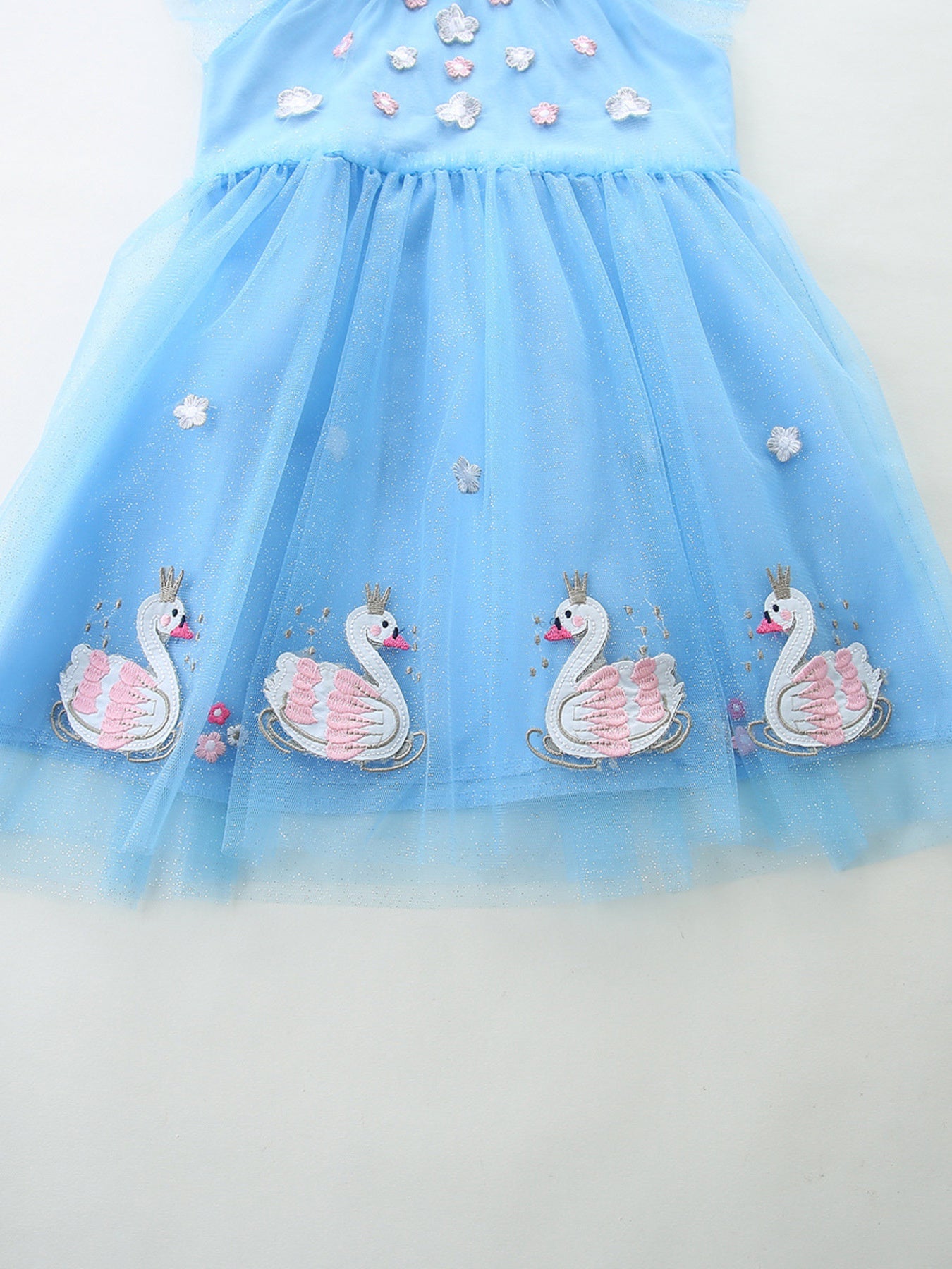 Blue tulle baby dress with swan embroidery and cap sleeves.