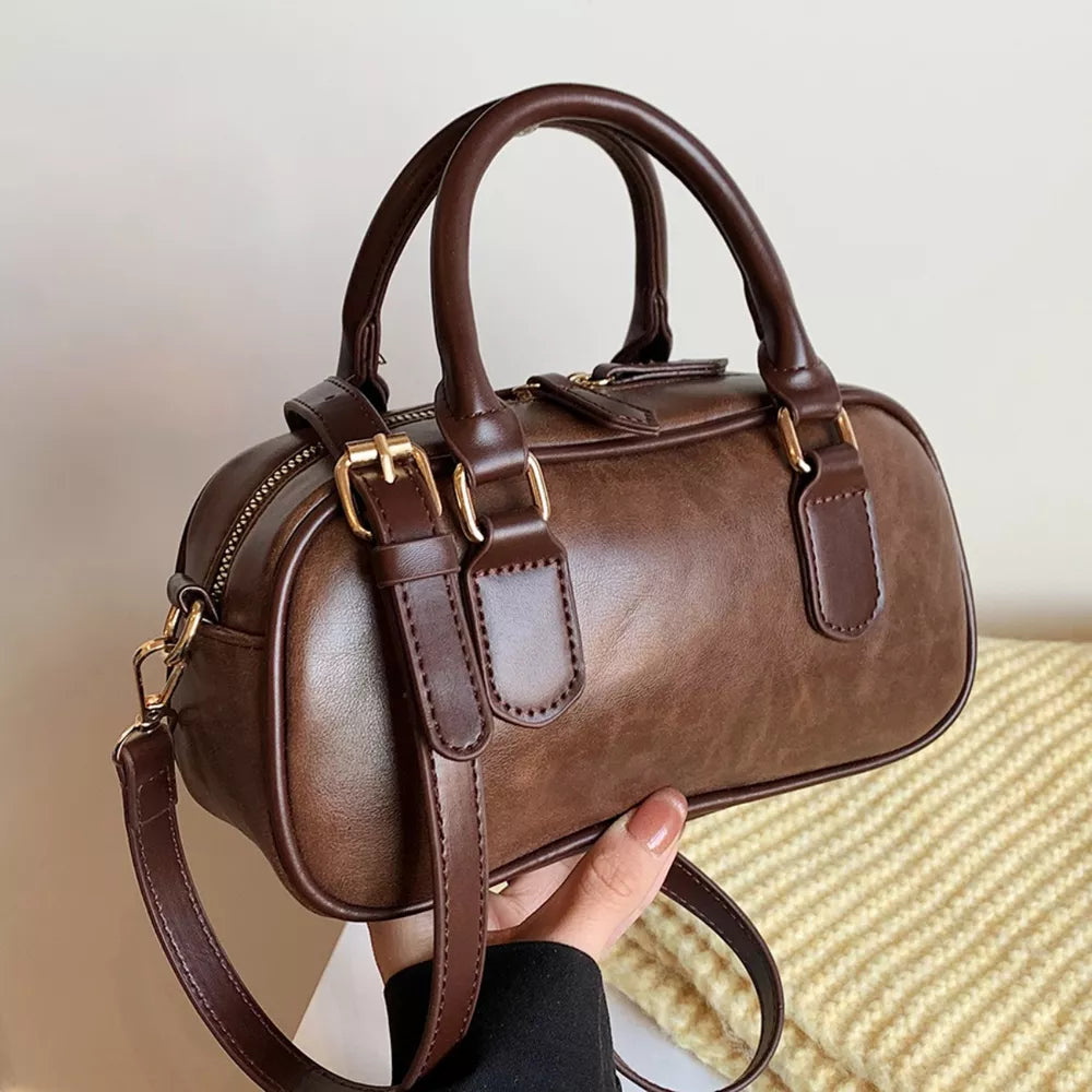 Chic mini barrel crossbody bag in brown faux leather with gold hardware and top handles.