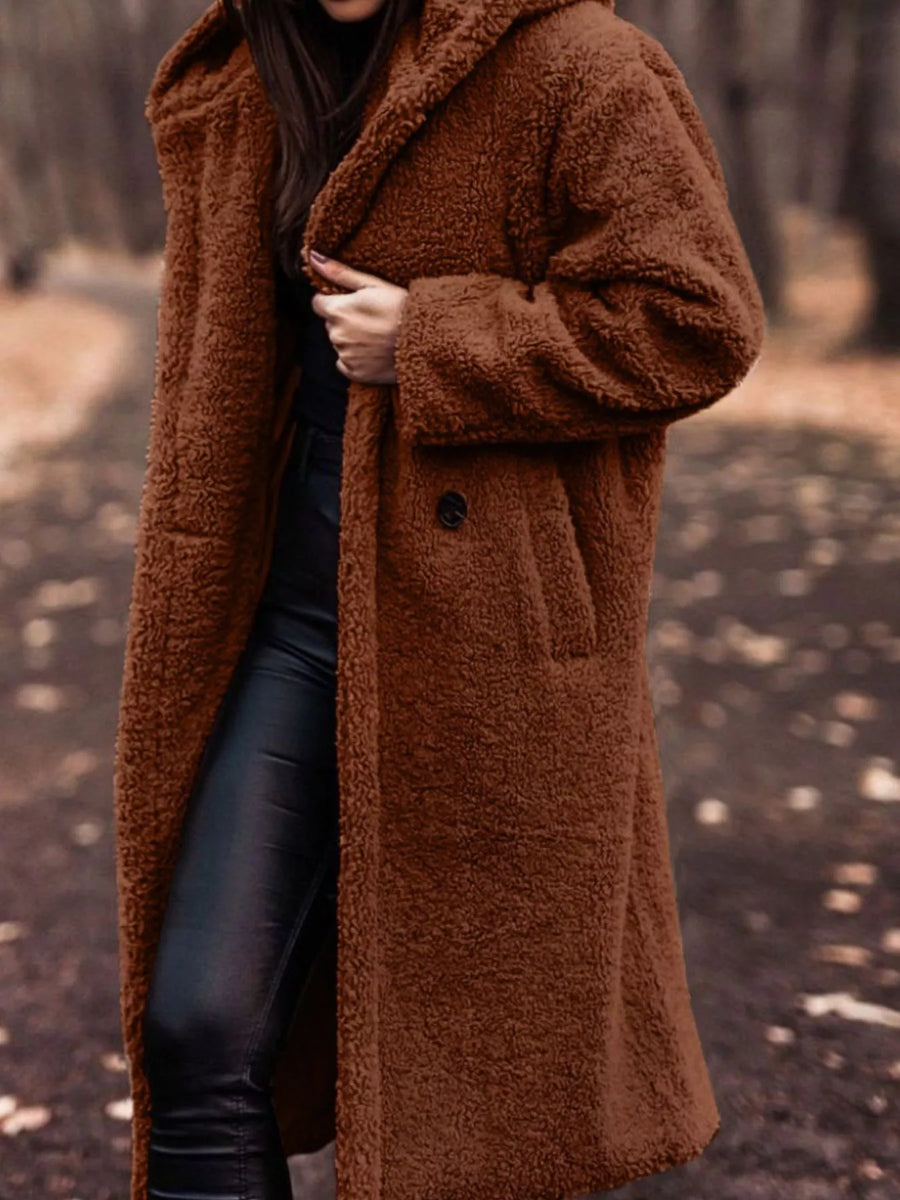 Brown teddy bear longline coat with hood and button closure, styled with black pants.