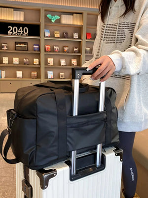 Black Oxford cloth travel duffle bag with adjustable strap and exterior pockets.