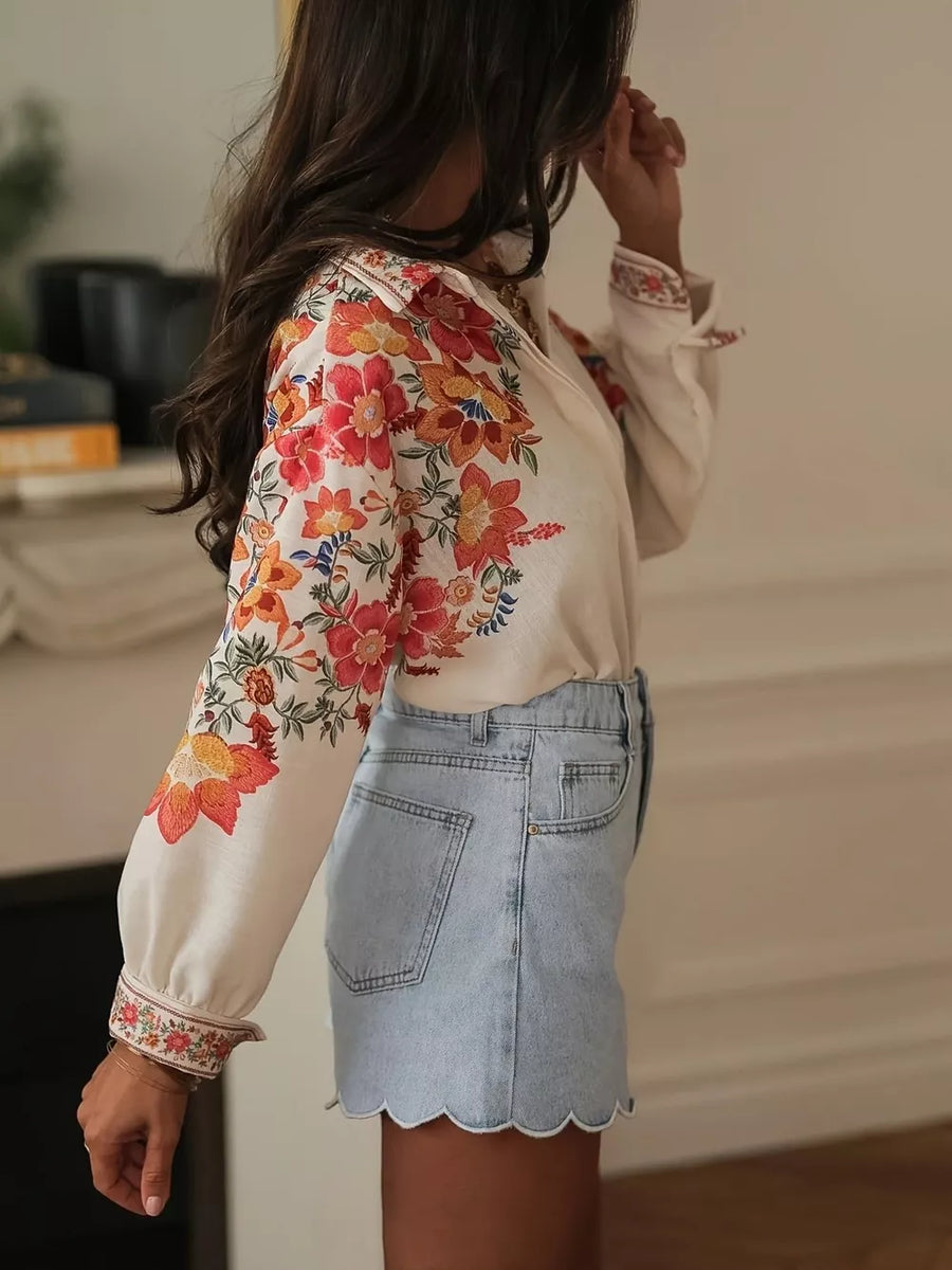 Cream embroidered floral blouse with long sleeves and light wash denim shorts with scalloped hem