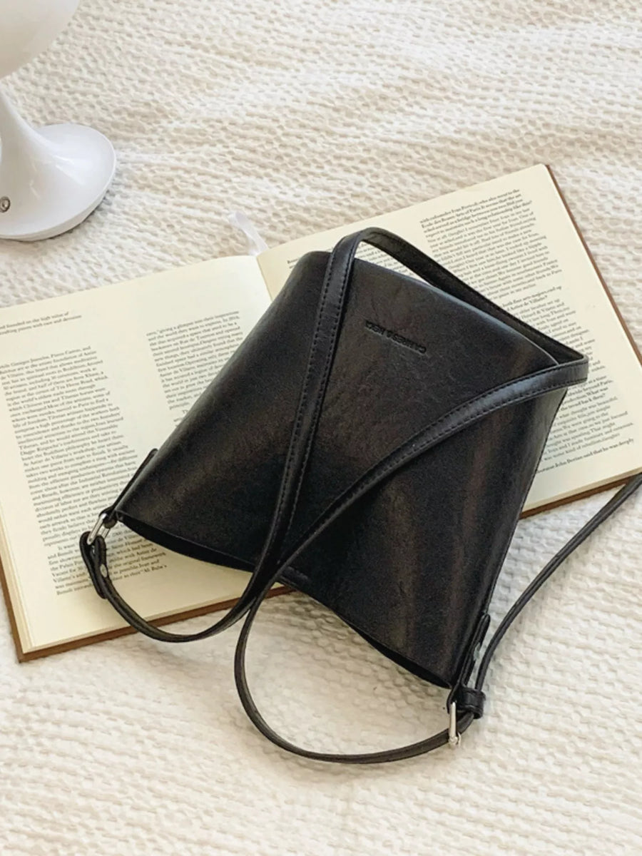Black leather bucket crossbody bag with adjustable strap and subtle embossed logo.