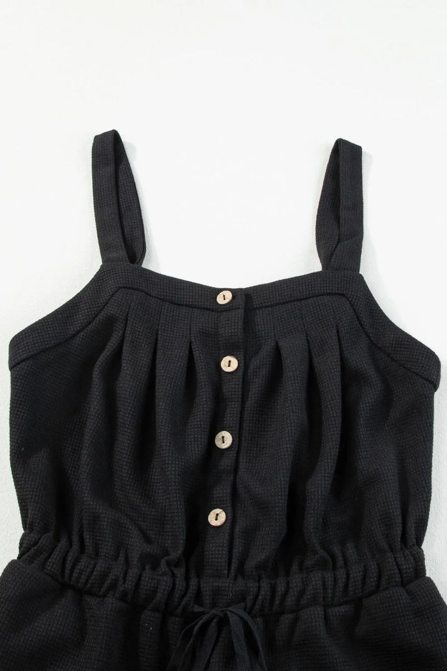 Black waffle knit jumpsuit with button front, drawstring waist and wide legs.