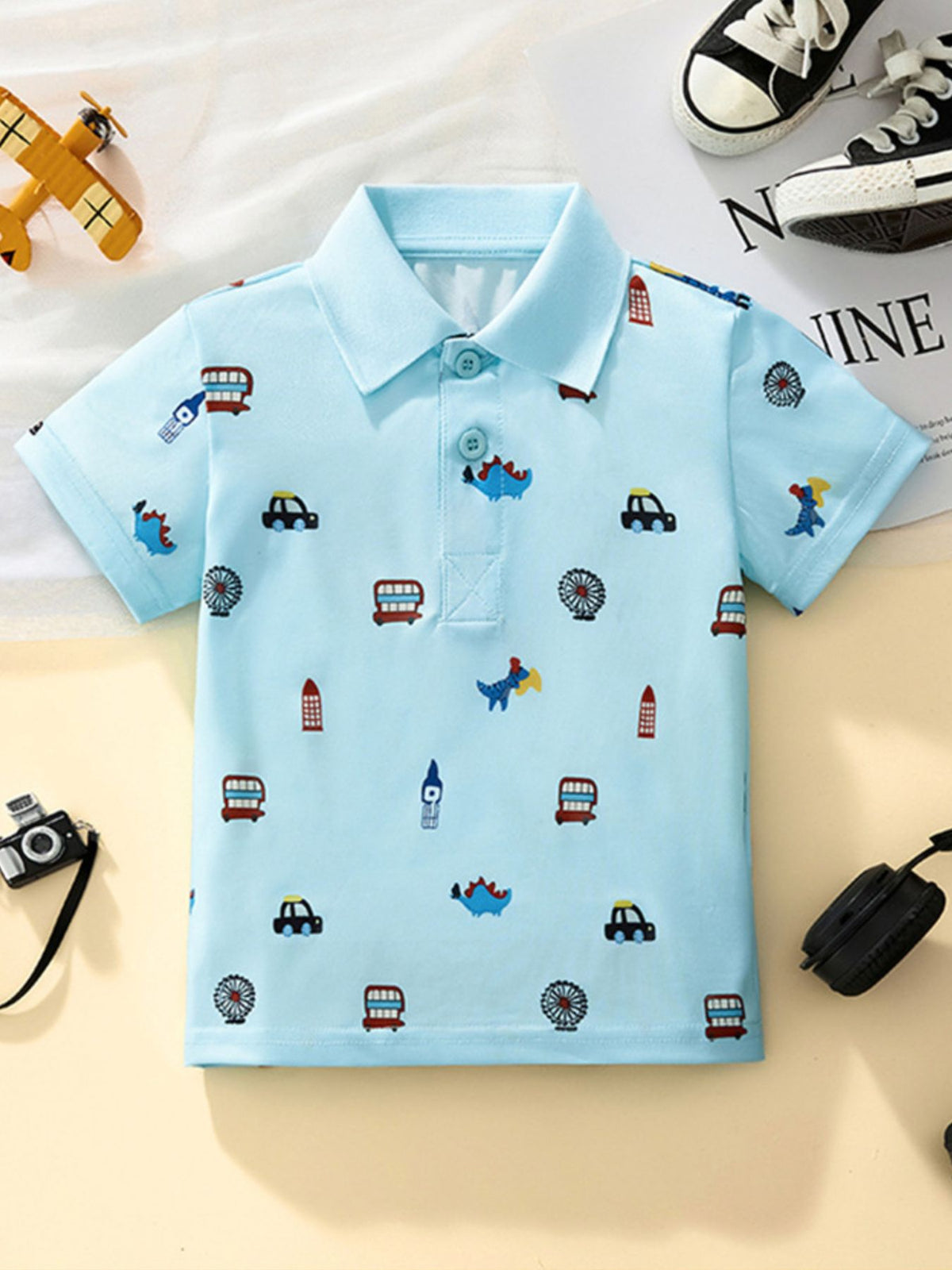 Light blue toddler polo shirt with cartoon cars and dinosaurs print