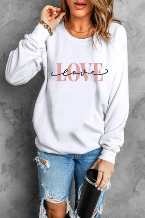 White crewneck sweatshirt with pink "LOVE" graphic and script detail.