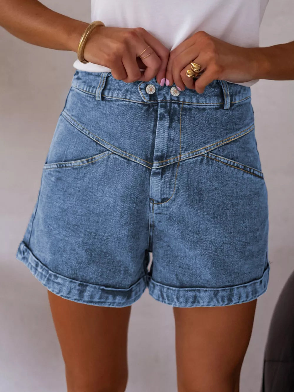 Blue denim shorts with high waist, angular seams, button fly, and cuffed hem