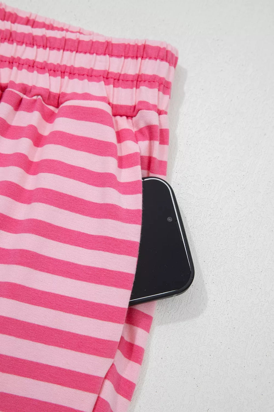 Chic pink striped cotton two-piece set with buttons and a pocket holding a phone.
