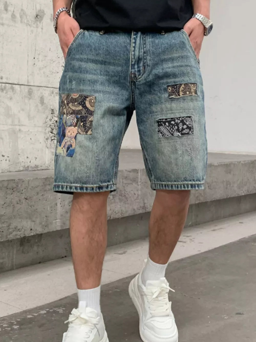 Men's denim shorts with graphic patchwork details and a distressed wash.