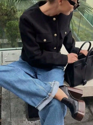 Black cropped tweed jacket with gold buttons and chest pockets.
