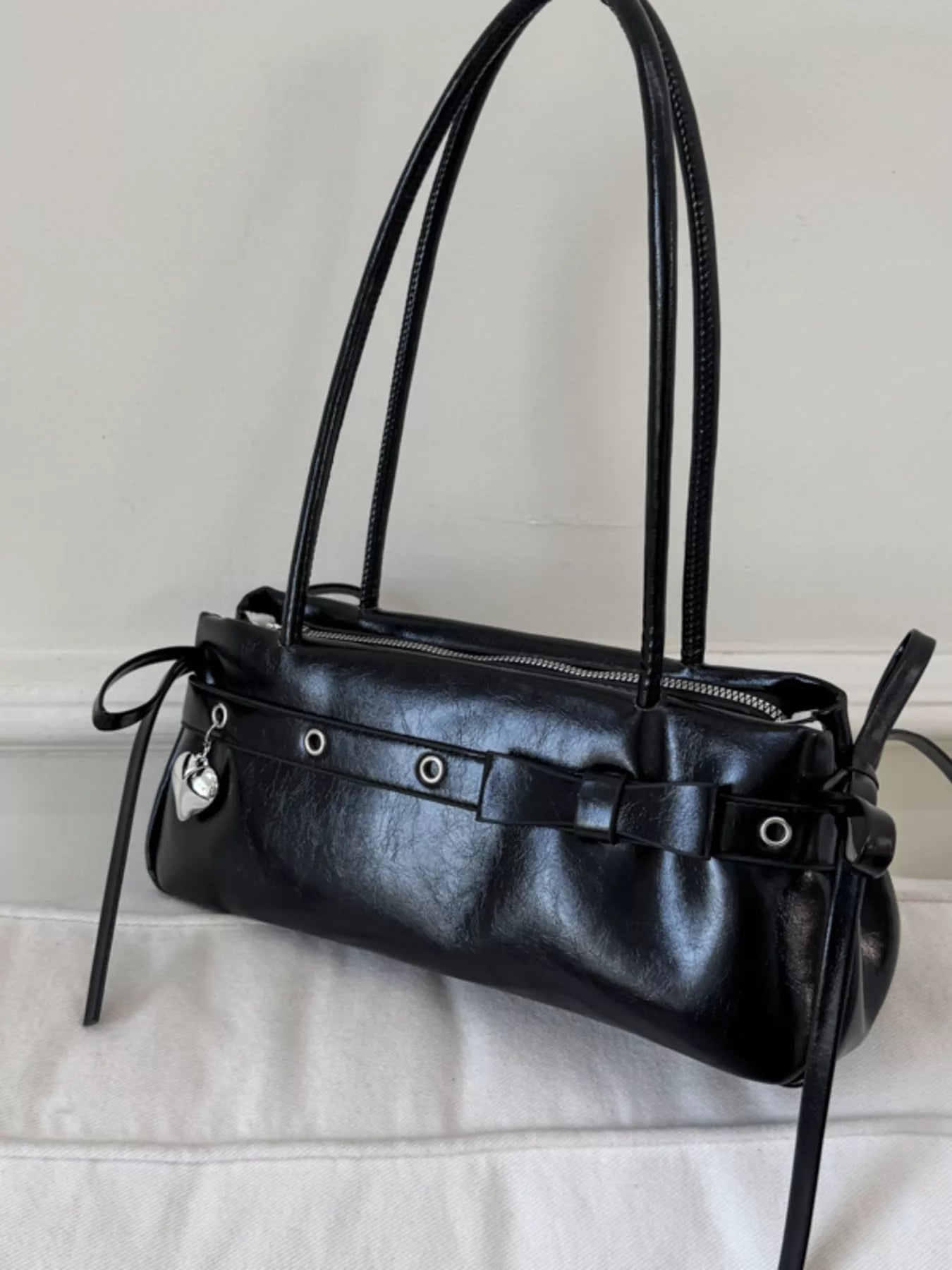 Black PU leather shoulder bag with silver heart charm and buckle details.