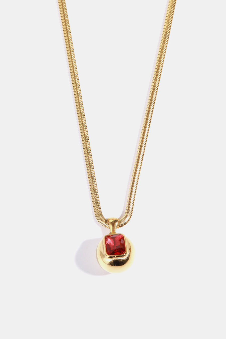 Gold necklace with orb pendant and deep red square stone