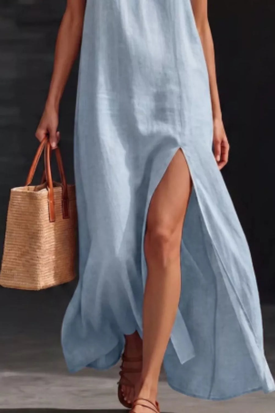 Light blue V-neck maxi dress with high slit, sleeveless, and a straw tote bag.