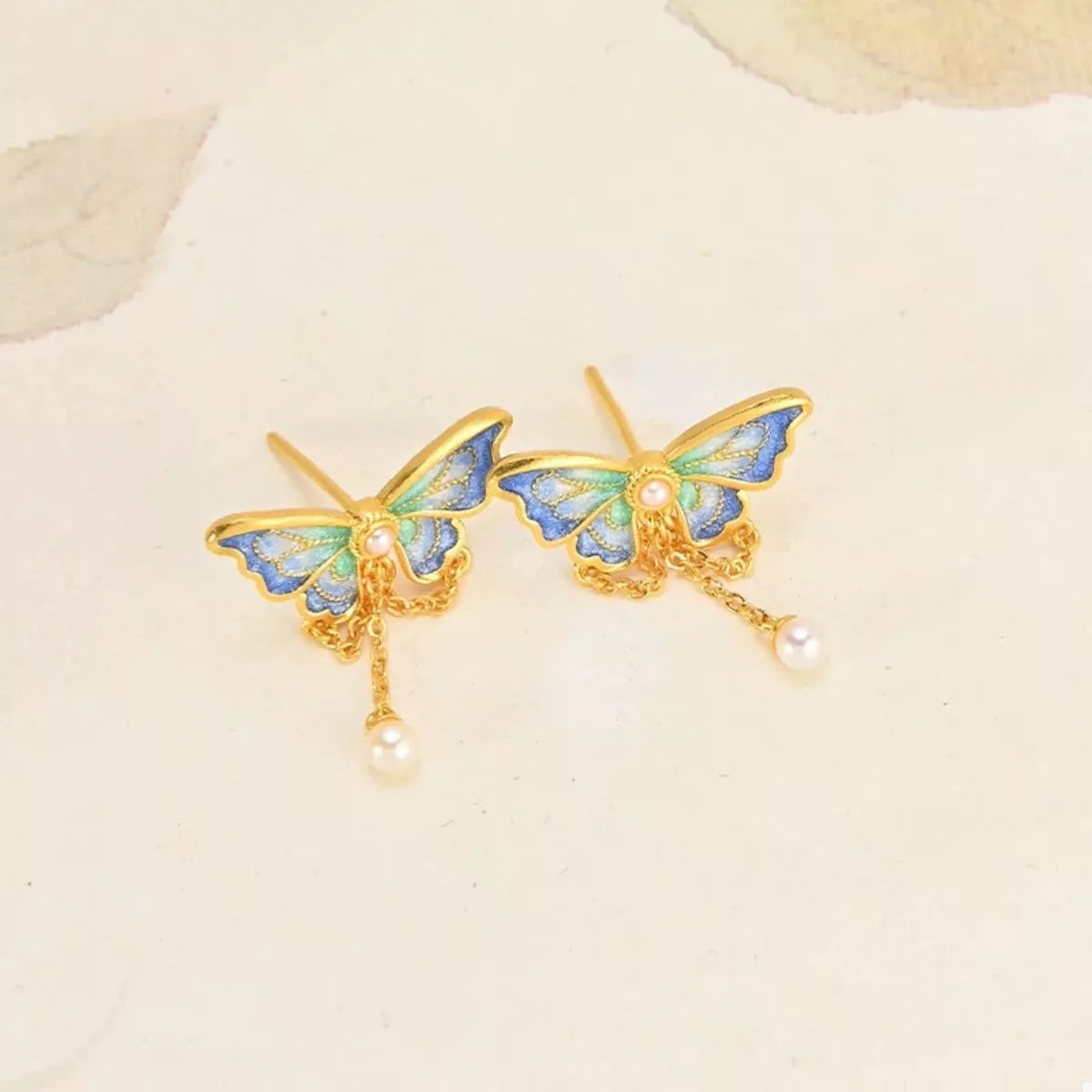 18K gold-plated butterfly earrings in cerulean blue with pearl drops.