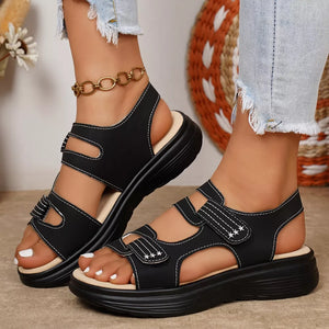 Black adjustable platform sandals with white stitching and ankle strap detail.