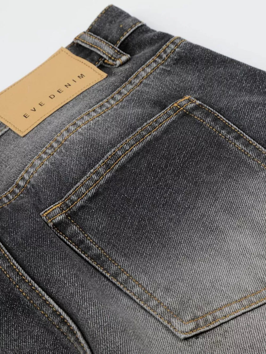 Men's black distressed wide-leg cotton jeans with tan leather back patch.