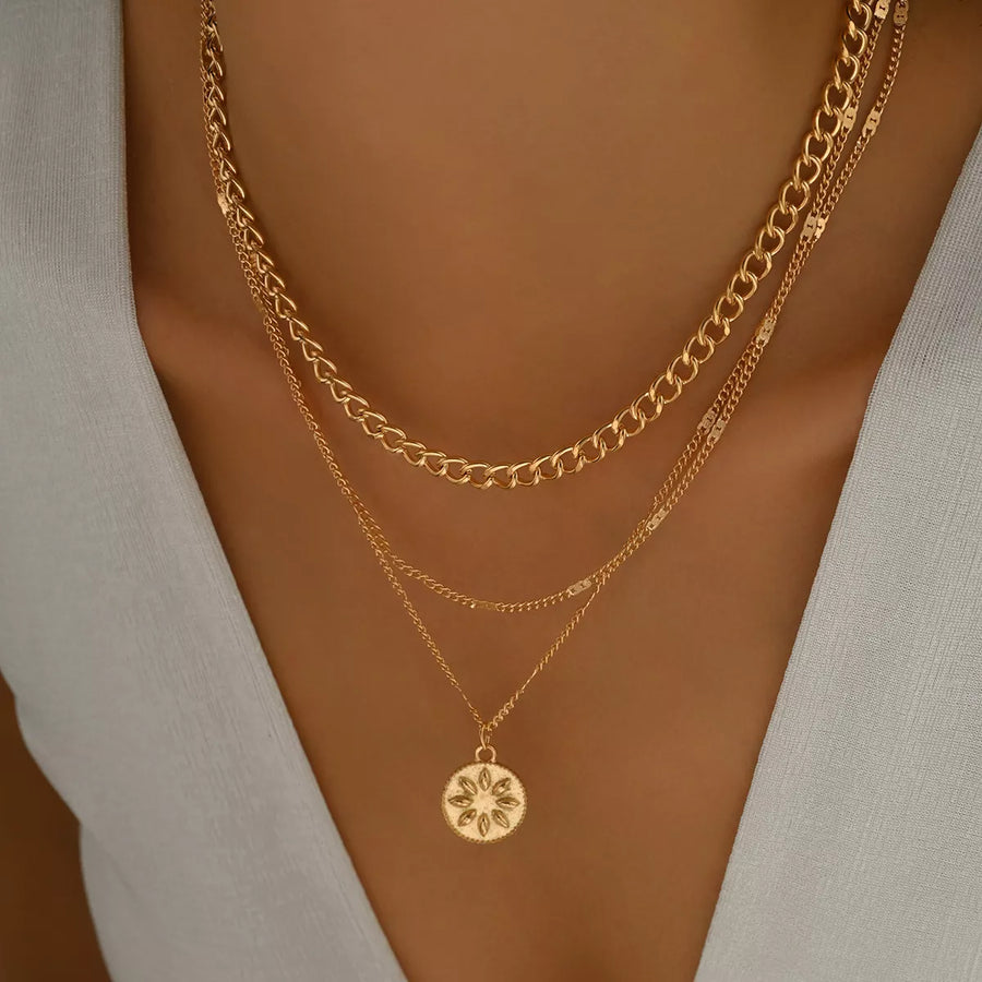 Gold layered necklace with curb chain and coin pendant detail