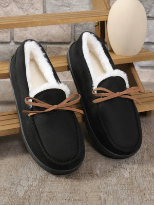 Black suede moccasin slippers with white faux fur lining and decorative bow detail.