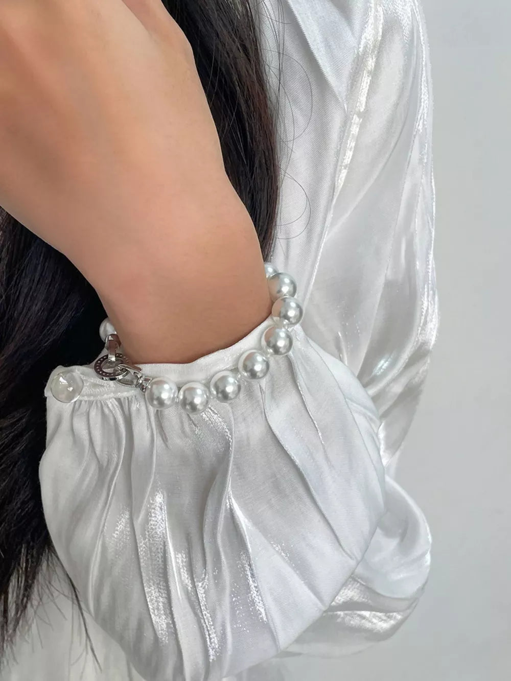 Elegant white pearl beaded bracelet with silver clasp detail on wrist.