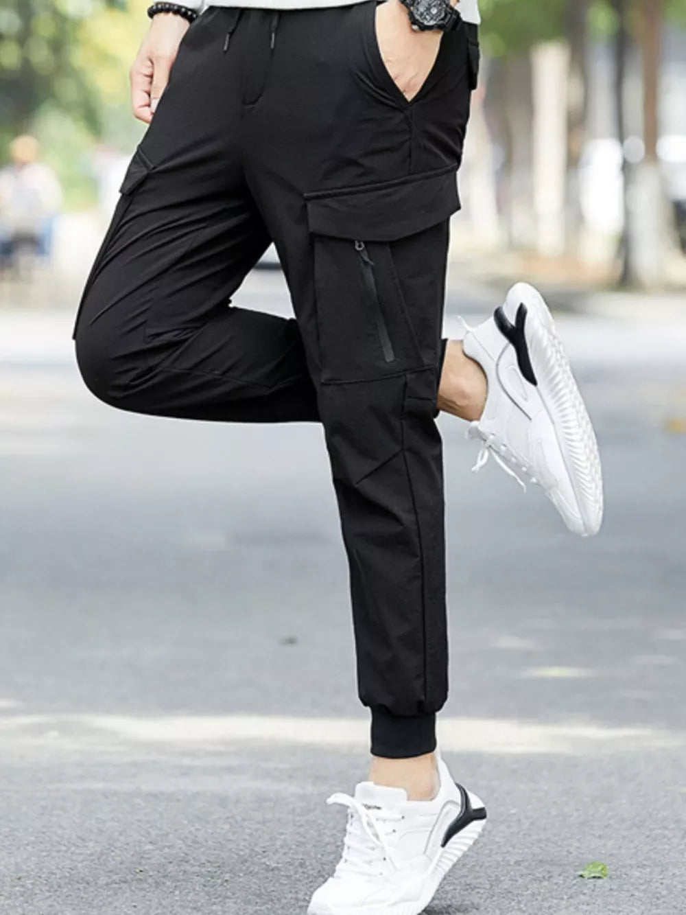 Black cargo joggers with zippered pockets and drawstring waist, styled with white sneakers.