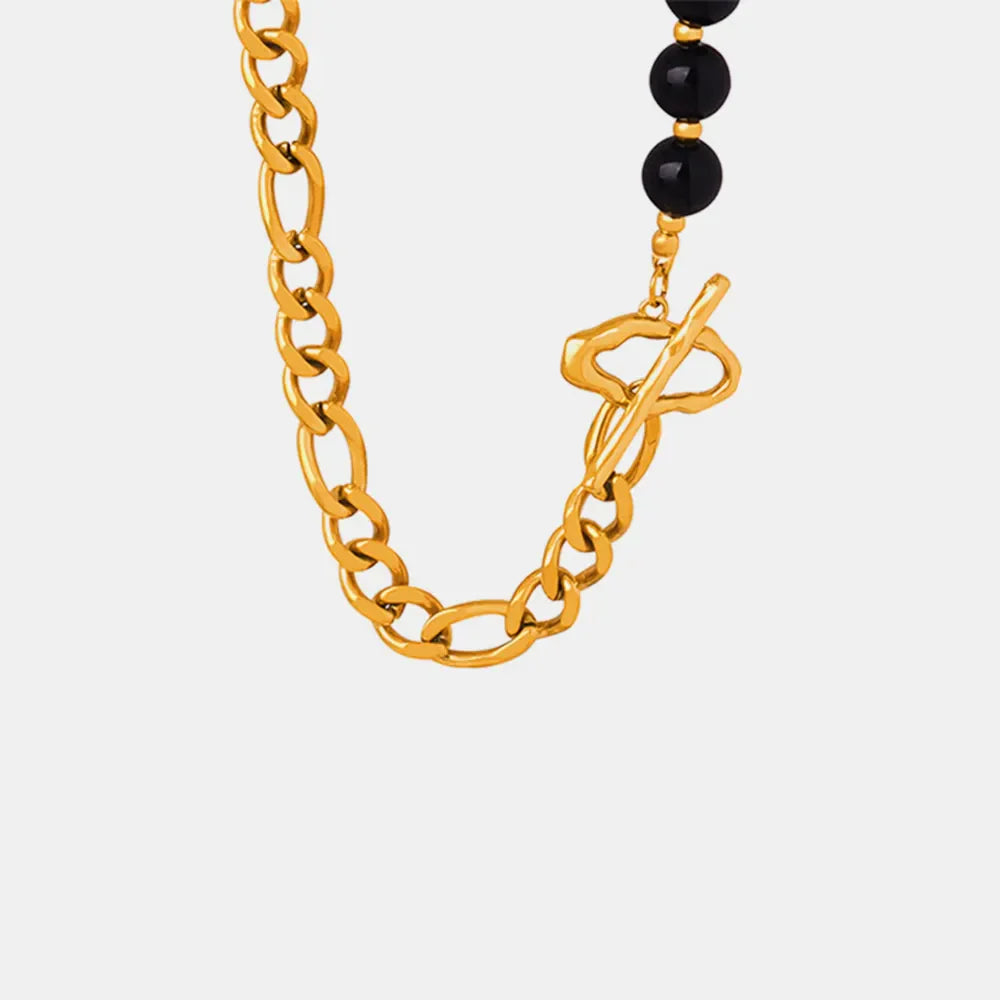Gold asymmetrical beaded chain necklace with black agate beads and toggle clasp.