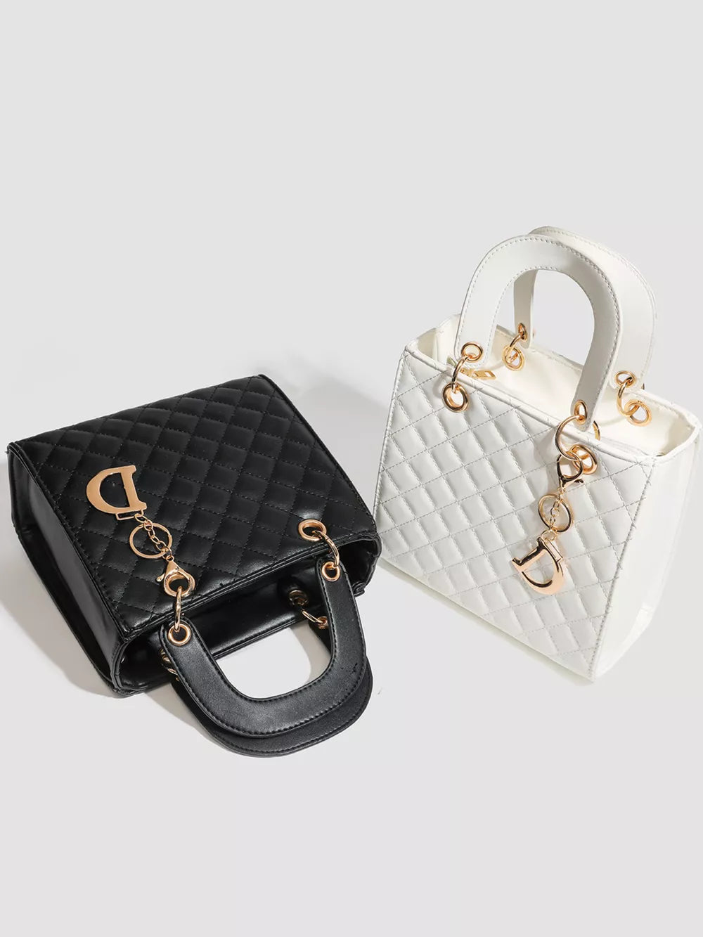 Mini quilted top-handle tote bag in black and white with gold hardware and charm.
