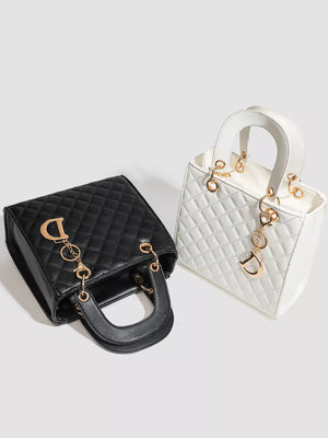 Mini quilted top-handle tote bag in black and white with gold hardware and charm.