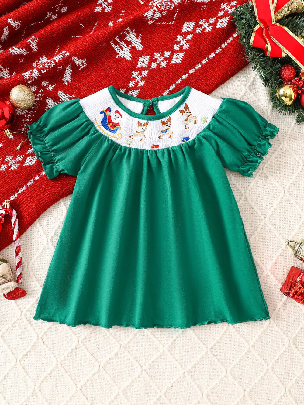Green A-line baby dress with smocked yoke featuring Santa and reindeer embroidery, puff sleeves.